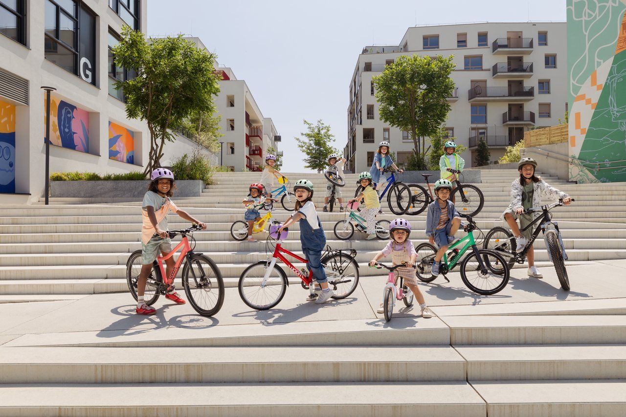 Children with woom bikes on outdoor steps